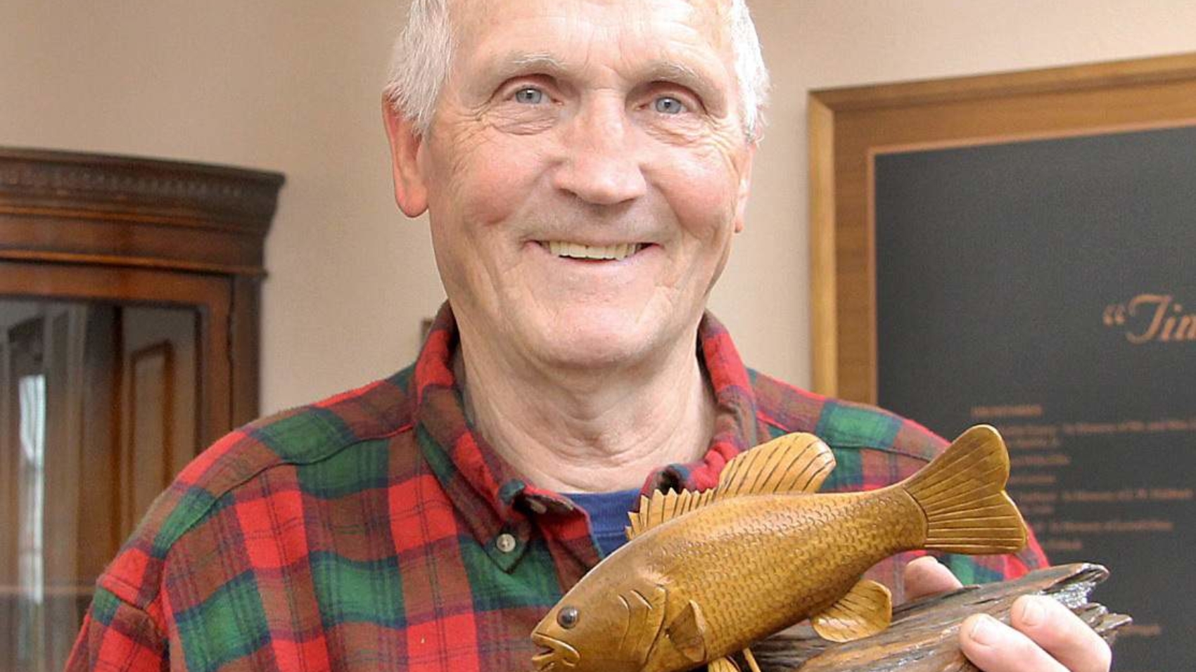 Tony Fornelli poses with a wooden fish carved by him.