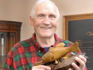 Tony Fornelli poses with a wooden fish carved by him.
