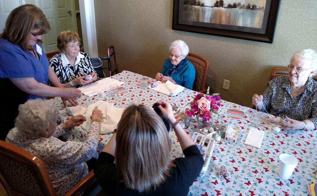 CNA Linda Adams helps Bonnie Lewis, Velma Williams, Jean McFarland make Easter eggs out of fabric.