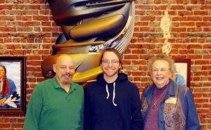 Mary Johnson, right, her son, Greg, left, and grandson Webster. Greg is a sculptor who created the artwork directly behind them.
