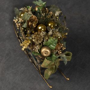 Christmas Forever - Detail image of sleigh basket with gold Christmas ornaments and pinecones finished off with green bow