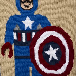 Fiber Arts - Captain America - Detail - Crochet afghan in red, white and blue yarn. White stars in each of the four corners frame the image of a lego sytle figure of Captain Ameria.