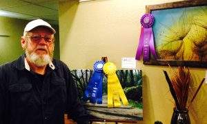 John King poses with his pieces “Walk in the Woods,” which is People’s Choice Professional, and “Bubbles,” which was Best in Show Professional.