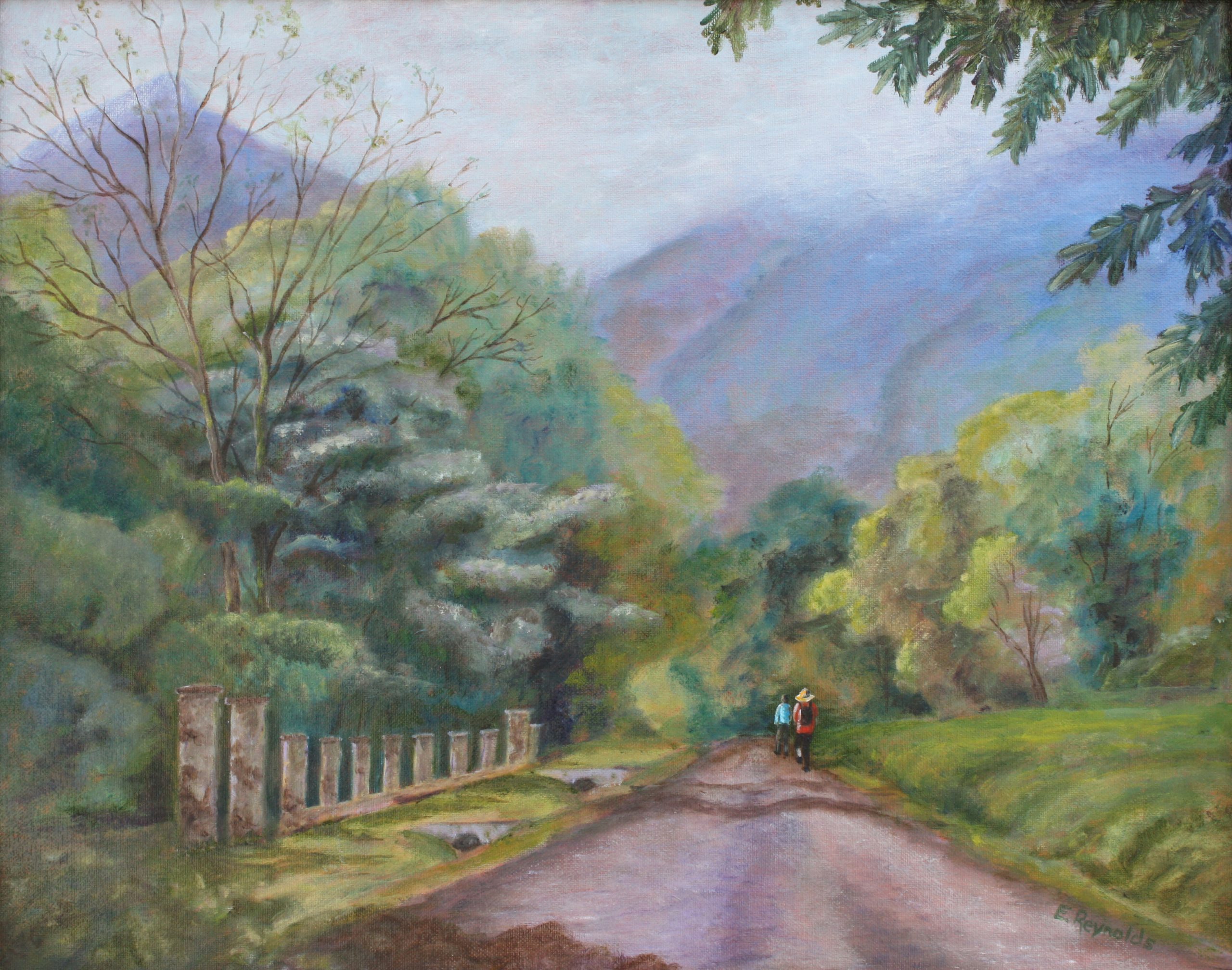 A landscape of a road with two people walking on it in the distance with mountains in the background.