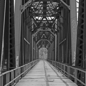 Photography - Carpenters Bluff Bridge - black and white photograph of an iron truss bridge that spans up the sides and over the top of the bridge.