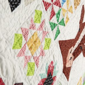 Quilting - Farm Girl - Detail - quilt made of a varitey of patterned fabrics made into blocks to make images of a red barn, sunflowers, cow, hen and chicks, sheep and bumble bee. The quilt has a very whimsical theme and was made for a girl.
