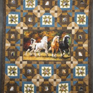 Quilting - Horses on the Run - quilt made of blue, brown and gold patterned fabrics with a large block in the center with four horses running on the prarie. Surrounding blocks on the quilt each showcase an image of a different horse.