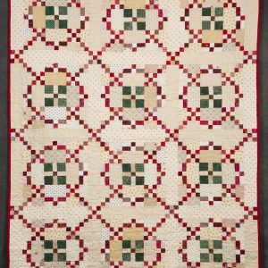Quilting - Merry Merry Christmas Throw - quilt made from small fabric blocks of patterned red, green, beige and white designed in a motif with twelve circle shapes all connected with small blocks giving a crisscross effect.