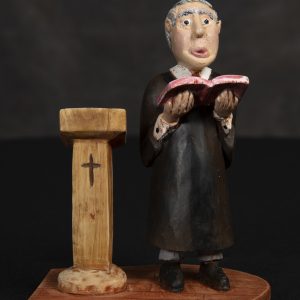 Sculpture 3D - Country Parson - sculpture of county parson in a black clergy robe holding red bible/book standing next to a pulpit with cross carved on it.