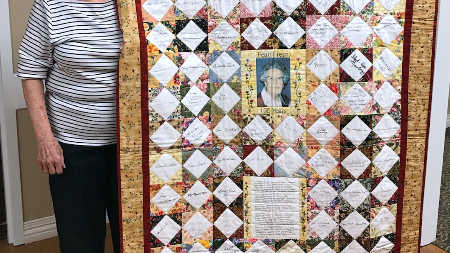 Leta Sherwood poses with the quilt she made to celebrate her mother's 100th birthday. The quilt included blocks of fabric signed by family, friends and even President G.W. Bush.