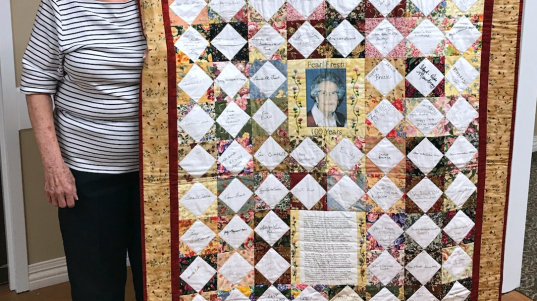 Leta Sherwood poses with the quilt she made to celebrate her mother's 100th birthday. The quilt included blocks of fabric signed by family, friends and even President G.W. Bush.